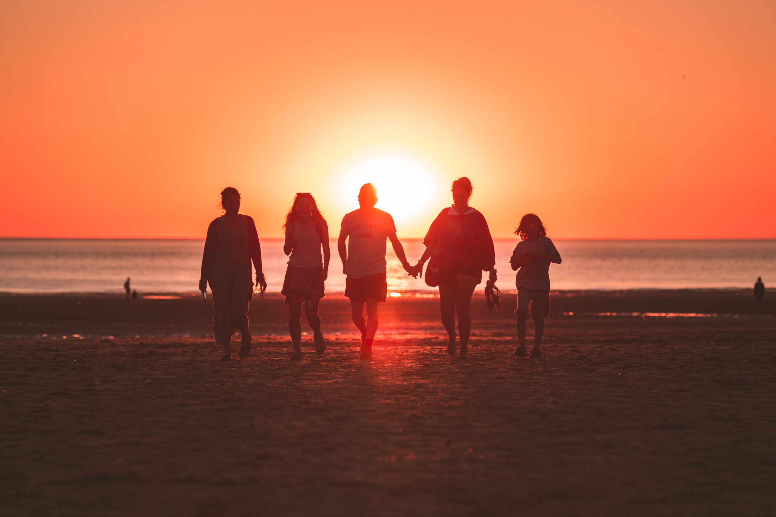 family walking on beach at sunset